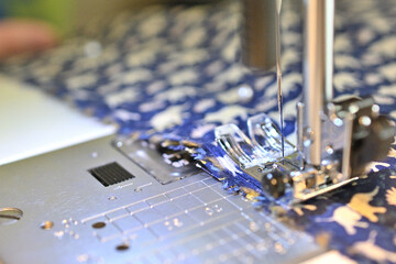 ミシンを操作する手。手で布を送っている。