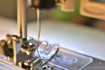 ミシンの台と押さえのクローズアップ。糸が出ている。