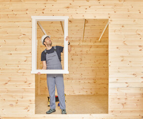 Construction man, builder man construct new wooden home, tiny house style. Spirit level, screw, tool bag and charged drill. Wood shelter style.