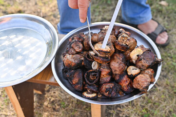 fried juicy meat kebab is removed from the skewer into a metal tray
