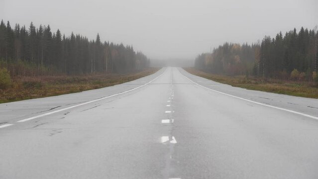 A drive through a forest on a rainy day in Finland. The camera is mounted to the dashboard of a car, giving viewers a first-person perspective. The road is empty and the weather is bleak, creating a s