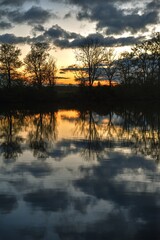 Serene sunset over a French river with calm waters reflecting clouds and shoreline trees