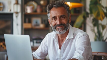 Obraz premium Work online as an entrepreneur with a laptop computer in an office. Happy middle age man, entrepreneur, small business owner.