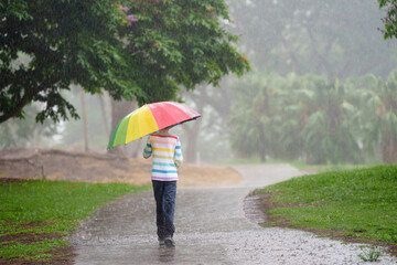Obraz premium Child playing in rain. Kid jumping in puddle.