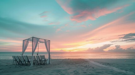 A minimalist beach wedding setup with a simple white canopy, the chairs facing a serene sunset that fills the sky with pastel colors.