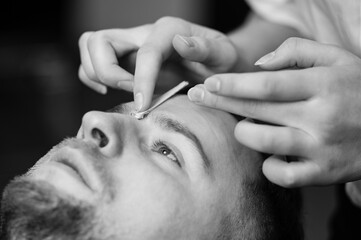 Hair removal procedure in a barbershop. Eyebrows hair wax removal.