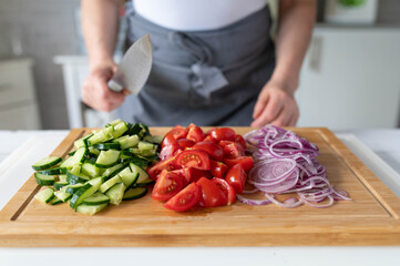 Woman with knife in her hands and chopped vegetables on a cutting board