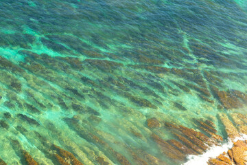 Aerial view of ocean waves crashing against rocks on the shore. Sea water background