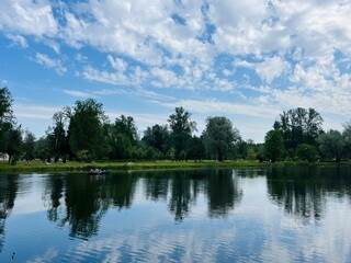 Green trees and sky reflection on the water surface, pond in the park