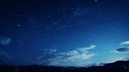 A night sky over mountains with scattered stars and clouds