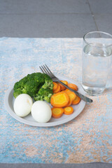 A breakfast diet plate without rice, featuring eggs, carrots, and broccoli, promoting a healthy and balanced meal