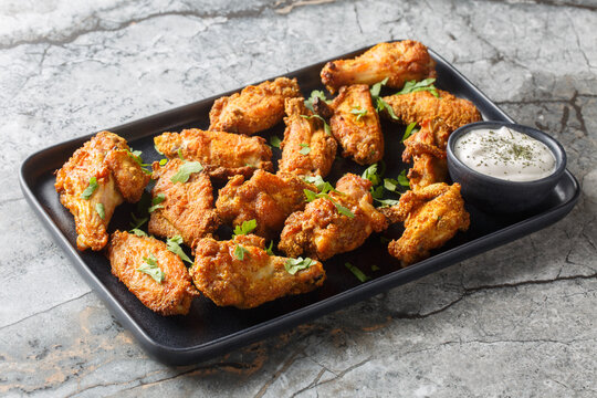 Spicy crispy baked chicken wings breaded with curry close-up in a plate on the table. Horizontal