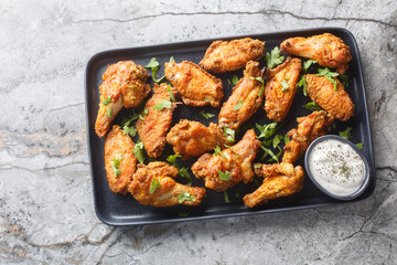 Homemade baked chicken wings breaded with curry close-up in a plate on the table. Horizontal top view from above