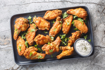 Spicy crispy baked chicken wings breaded with curry close-up in a plate on the table. Horizontal top view from above