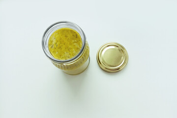 Pesto sauce in a glass jar, open lid. White background. View from above.