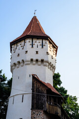 Fototapeta premium Large old white painted stone tower in the historical center of the Sibiu city, near Citadel Street and Park (Strada si Parcul Cetatii), in Transylvania (Transilvania) region of Romania, in summer.