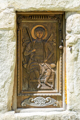 Beautiful wooden carved door to the church with the image of a saint sitting on a throne