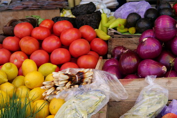 Lemons tomatoes and onoins on a table at a market close up.
