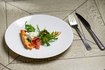 piece of pizza with smoked salmon and arugula on a white plate