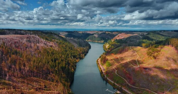 Dramatic cloudscape hanging in the sky over the mountainous landscape of Oregon. Drone flight over the beautiful river flowing among the mountains.