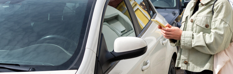 Female person unlocks remotely free-floating car-sharing car on city street. 