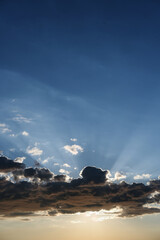 the sun's rays are visible through the clouds. blue sky with clouds and sun rays.