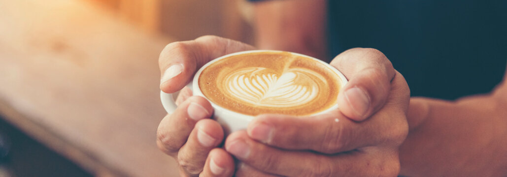 Banner Coffee barista pour espresso shot and make latte art hot coffee cup. Cappuccino with milk in italian coffee shop cafe. Banner Close up hands of barista make brown latte art with copy space