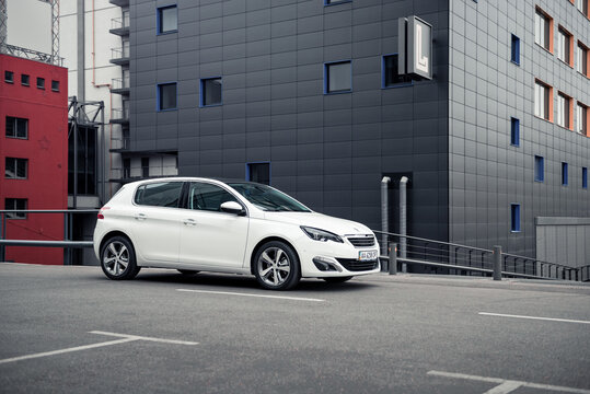 Kyiv, Ukraine - September 21 2015: white Peugeot 308 hatchback in front of the corner of anthracite modern building. three quarter view of compact car