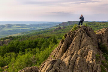 a young handsome man travels through the mountains of the Southern Urals on a summer day