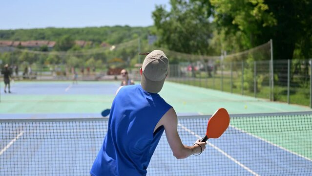 A man and a woman playing pickleball on a sunny day