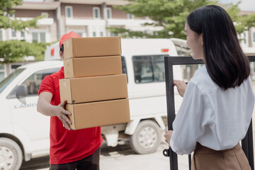 Young courier in red suit holds cardboard parcel box and woman transfers money with mobile to pick...