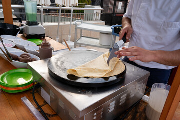 A man is making a dessert on a pan. The pan is on a table with other items