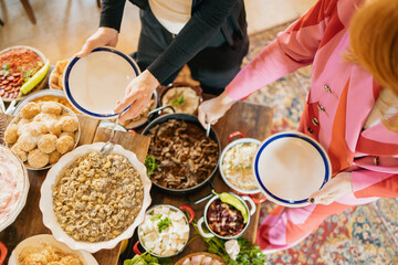 Hands picking up delicious food from buffet assorted on wooden table in restaurant.
