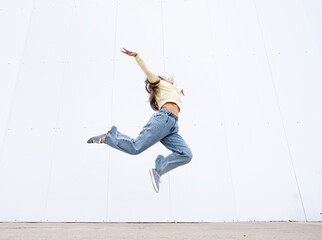 plus size woman wearing casual clothes dancing on white wall background in the street
