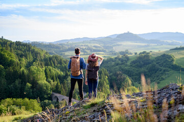 Travellers couple hiking on easy trail in nature with backpacks. Young tourist resting, enjoying...