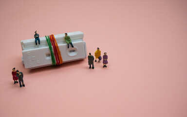 Covid-19 rapid antigen test cassettes tied with colorful rubber bands, decorated with few people...