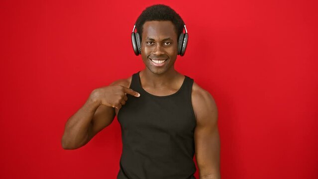 Young, proud african american man, bopping to music, confidently points at himself, beaming with happiness on an isolated, red background