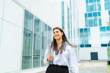 Fototapeta premium One young successful business woman going to work at business office modern building while holding coffee and laptop 