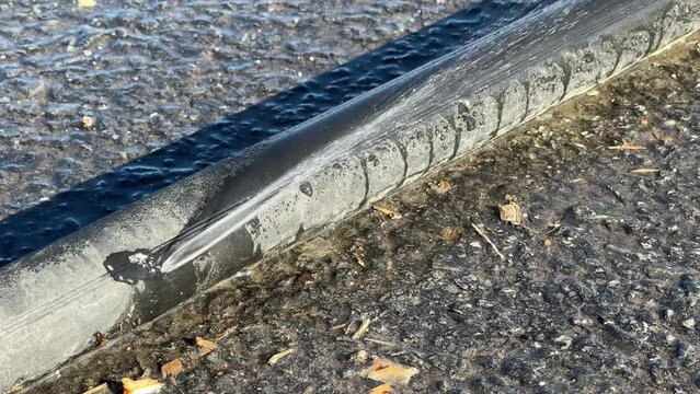 Leaking black polyethylene water pipe on ground outdoors