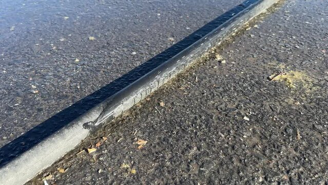 Leaking black polyethylene water pipe on ground outdoors