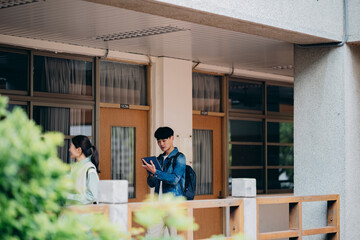 Asian university students walk out of the classroom, discussing their coursework as they go.	
