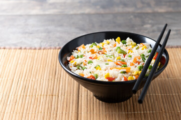 White fried rice with vegetables on wooden table. Copy space