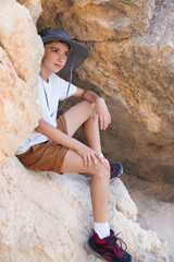 boy hiking in limestone mountain in spain with hat and trekking boots