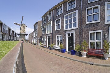 Picture of a typical Dutch windmill in front of a deserted street against a blue sky