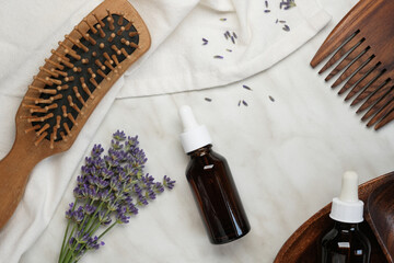 Top view natural lavender cosmetic on a marble background. Flat lay lavender flowers, wooden comb and essential oil. Skincare and body treatment concept. 