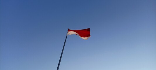 Indonesian flag blowing in the wind against a blue sky background