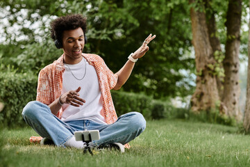 Young man of African descent sitting on grass, energetically pointing at phone.