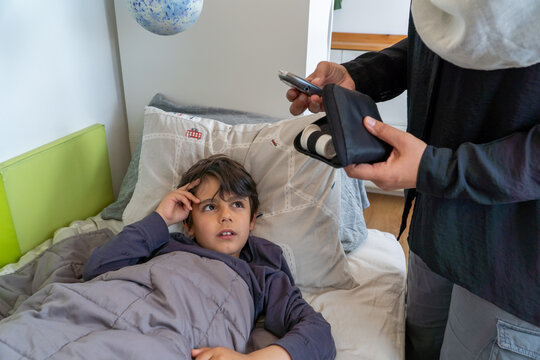 Anonymous mother checking hypoglycemic son's forehead in bedroom