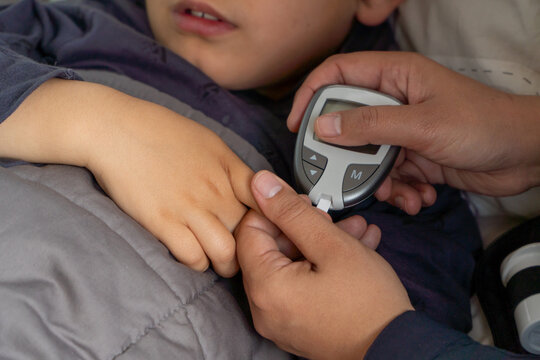 Cropped unrecognizable child receives glucose check during hypoglycemia episode by mother