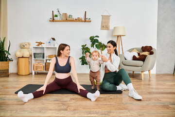 A young beautiful mother sits on a yoga mat, cradling her baby, with the guidance of her coach at parents courses.
